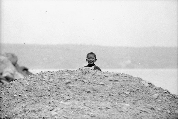 A young, smiling Black boy looks over a pile of debris at Africville in 1965.1196